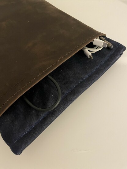 Top edge of the WaterField Folio Laptop Sleeve showing a couple of cables and a pen peeking out.