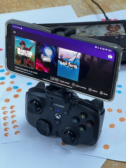 A Poco X4 Android phone clamped onto a small, black, portable controller. The mini-pad form of the Moga XP Ultra. The controller has full-sized analog sticks and triggers with full-sized button placement.