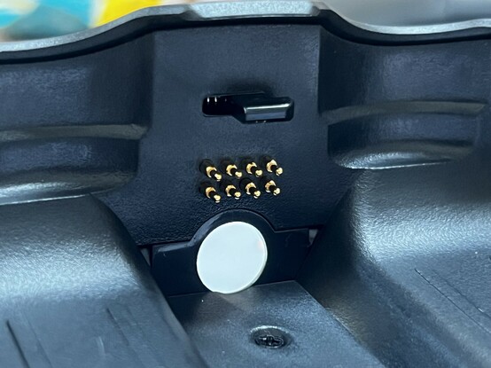 The inside of the controller hand-grip showing the pogo pins sticking out. There’s a hole for a 3.5mm audio jack to pass through and a little plastic clip to retain the mini pad controller.
