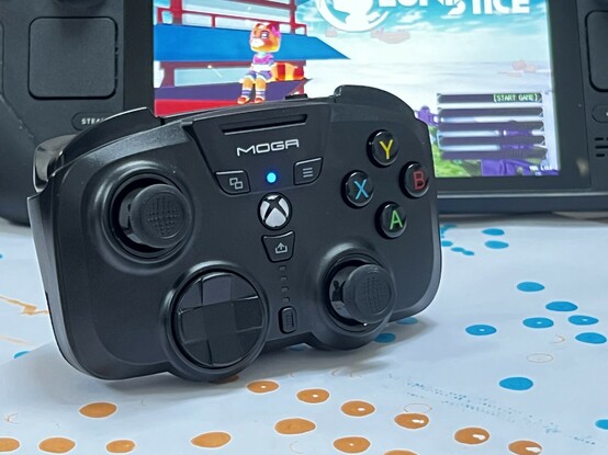 A mini game controller with full sized controllers posed in front of a Steam Deck. The Deck screen is lit up, showing the title screen for Lunistice.