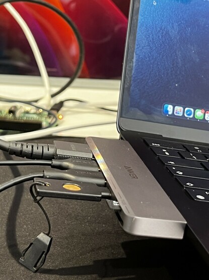 The Anker 7-in-2 USB Type C hub, plugged into a MacBook being lifted off the desk. Two USB cables and an HDMI cable are plugged in to weigh it down.