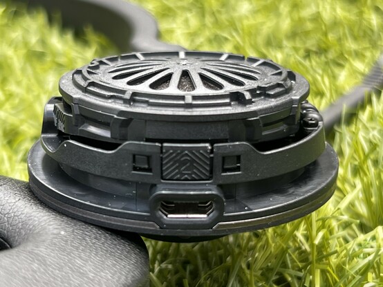 A close up of the Jabra Engage ear cup showing a little tab with chevron arrows and a number 2. It’s clear at a glance that you’re supposed to push the tab in and lift.