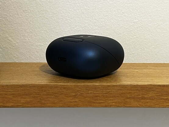 A little blue wireless earphone case sat upon the top wooden trim of a bed headboard.