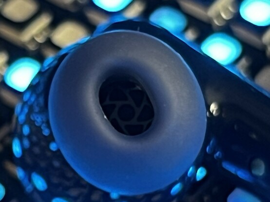 A closeup through the rubber ear piece showing the grille inside. More gloss reflections are blurred in the background.