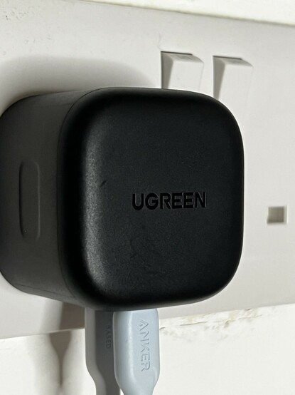 A photo of the UGREEN 65W adapter plugged into my office sockets with white and green Anker cables sticking out of the bottom. Controversial haha!