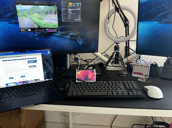 Two 4K monitors running from an M2 MacBook Air, accompanied by a third, tiny little 800x480, 7• LCD sat on the desk and showing a distinctly Mac wallpaper.