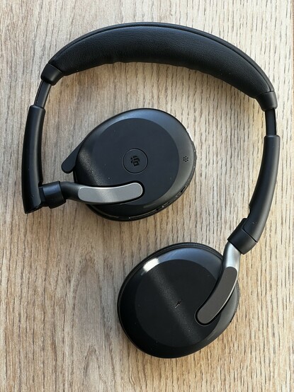 The Jabra Flex headphones lying flat and not completely folded. They are mostly black with steel grey accents where the head band joins to the cups.
