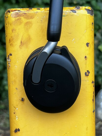 The right ear cup of the Jabra Evolve2 65 Flex set against a painted yellow metal post.