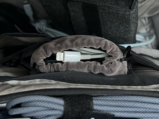 The UGREEN battery, barely visible inside it’s brown carry case and with a lighting cable stuffed on top of it. It’s tucked into an internal pocket of a chaotic backpack and fits quite handily. Though it’s a bit cozy.