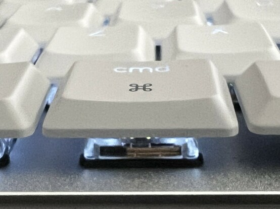 A closeup of the cmd key with the backlight on. The cmd text is very clearly lit up white, while the Apple command icon (a sort of four leaf clover design) is not lit at all, despite being part of the same transparent plastic under layer.
