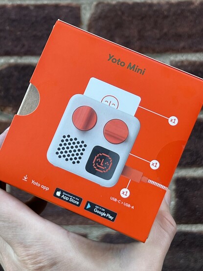 The very orange back of the box with the title “Yoto mini” across the top and a photo of the device, card, and USB cable that comes in the box. Each item is annotated with a little “x1” quantity marker to indicate the picture is representative of the box contents.