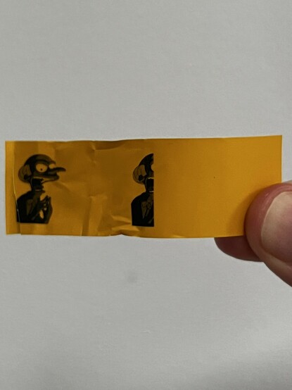 The mangled label held up, showing a complete Mr Burns image, dithered in black over the yellow background, and a second image cut off half way through as the printer gave up.