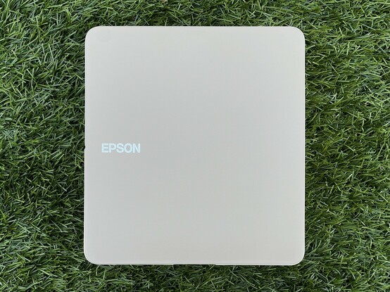 A top down shot of an Epson label printer lying on its side on grass. It’s effectively just a beige square with an Epson logo.