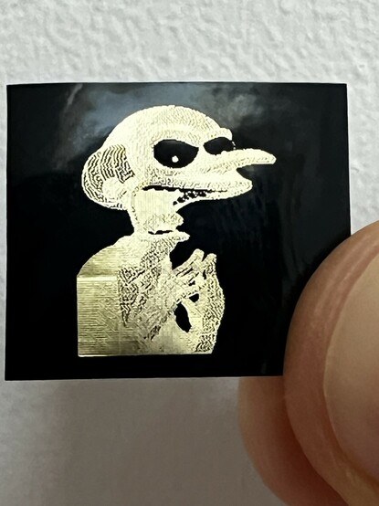 An error diffusion either of The Simpsons Mr. Burns in gold on black tape. His eyes are black with tiny gold pupils which looks positively demonic.