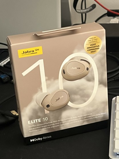 Photo of the Jabra Elite 10 box, it depicts the earbuds in front of clouds and a giant “10”. At the bottom is a “Dolby Atmos” logo. The box is mostly dark beige.