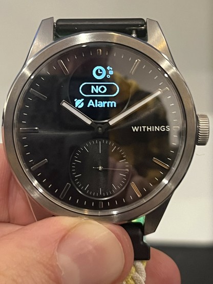 The ScanWatch 2 with the OLED showing alarm and clock settings. Some basic options can be changed on the watch. The view is very cluttered with a big NO in the middle to show the alarm is off, and a clock icon at the top with a little menu position guide next to it.