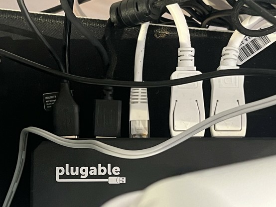 A top-down view of a USB Type-C docking station showing four USB devices, Ethernet and two DisplayPort cables connected. In the top left corner is a “plugable” logo.
