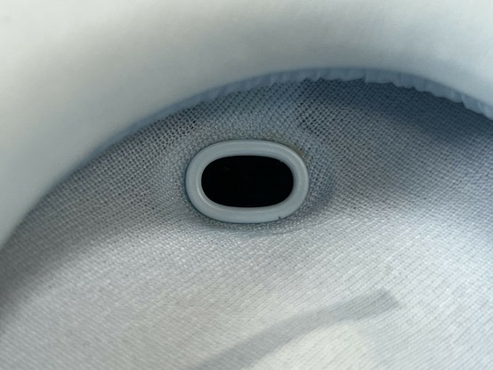 Extreme closeup of the inside of the left ear cup showing a small, oval window with a black abyss in the middle.