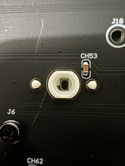 A closeup of the keyboard PCB showing the backside of a switch with the plunger fully depressed. A tiny magnet is nestled down within the plunger and is close to a little sensor labelled “CH53”.