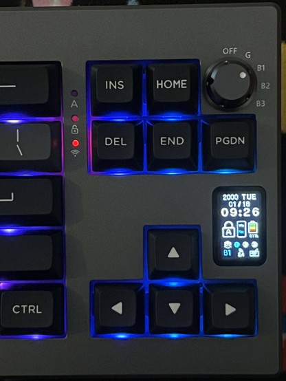 A top down shot of the right-hand edge of the Epomaker Shadow X. It shows the five position rotary switch nestled near Home and PgDn. It switches between off, 2.4GHz and three Bluetooth modes. Below the PgDn key is a small portrait OLED showing the date and a cluster of mismatched icons.