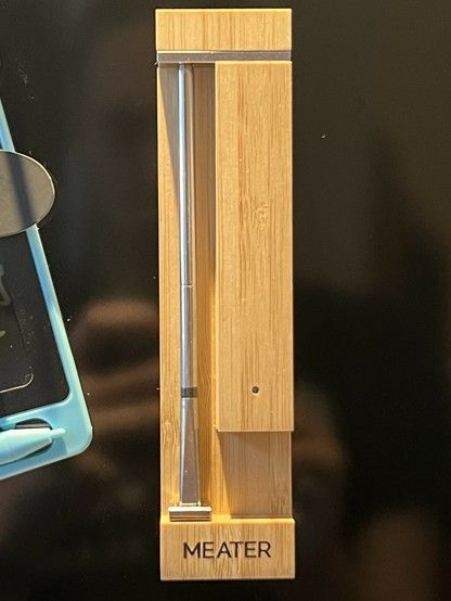 Wireless meat thermometer in a bamboo charging block with the word 