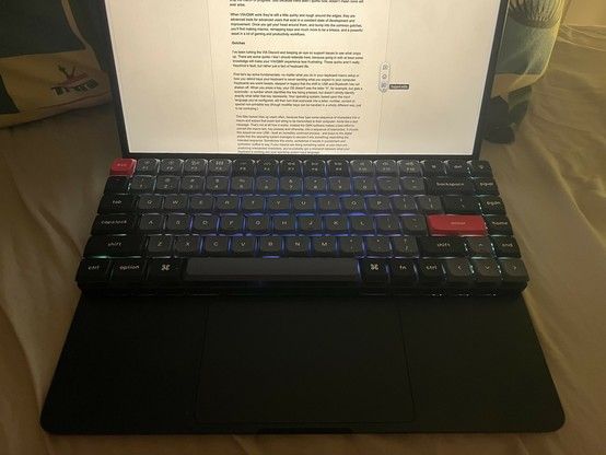 An open laptop with a glowing keyboard sat on top, that almost perfectly fits over the existing keyboard. A document is displayed on the screen.