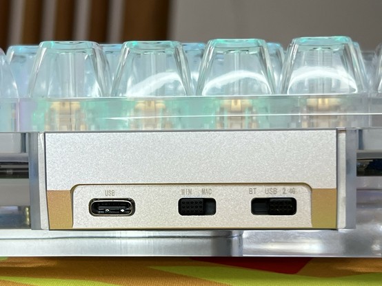 Close-up of a mechanical keyboard's connectivity ports and mode switches, including a USB-C port, a Win/Mac switch, and a BT (Bluetooth), USB, 2.4G tri-mode switch.