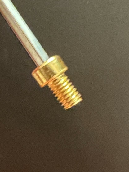 Close-up of a small gold-colored threaded bolt on the end of an Allen key.