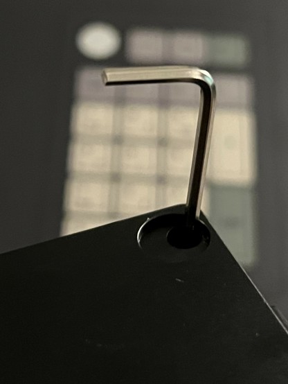 Image of an Allen key inserted into a black object, with a blurred background.