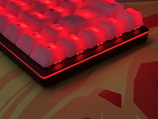 Close-up of a mechanical keyboard with red backlighting on the keys and base and a red lighting stripe around the edge.