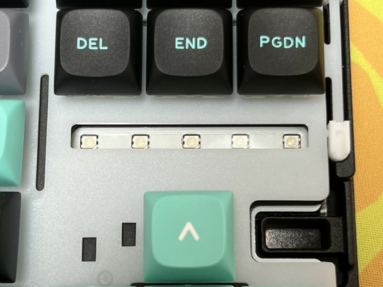 Close-up of a mechanical keyboard with the keycaps removed, exposing the LED lights and switches. Visible keys include DEL, END, PGDN, and an Arrow key.