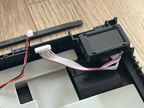 Close-up of internal electronic components with attached wires, positioned against a wooden surface.