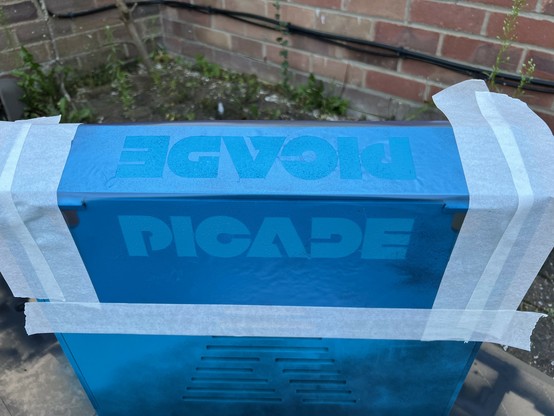 A blue-painted surface covered with a stencil featuring the word 