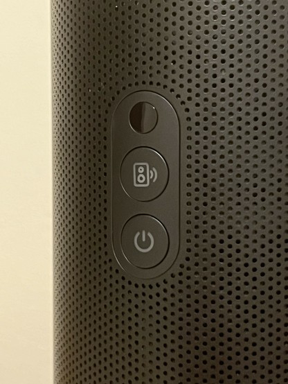 A close-up of the back of a mini projector with control buttons, including a power button and a Bluetooth speaker button.