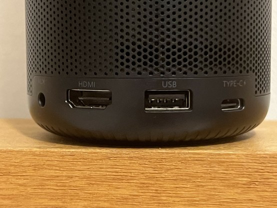 A close-up of the ports on the bottom of a black projector, featuring an HDMI port, a USB port, a Type-C port, and a 3.5mm audio jack.