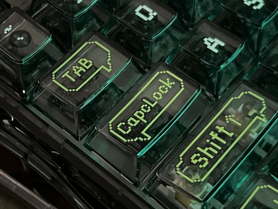 Close-up of a keyboard with translucent keys illuminated in green, displaying the labels 