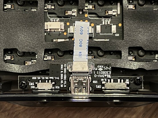 The inside of a mechanical keyboard showing the isolated USB daughter board connected via a flat flex cable. Wait is that a solder bridge!?