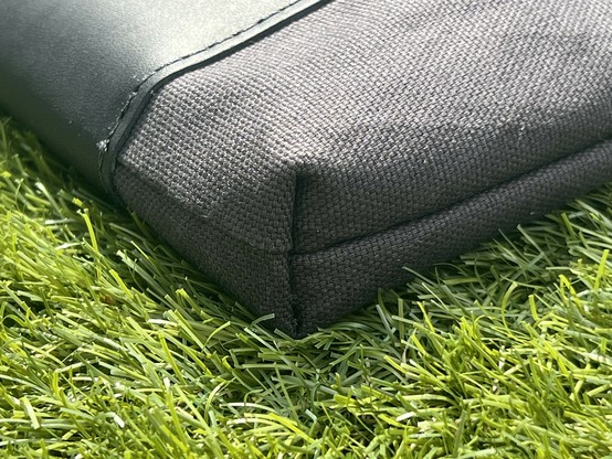 The corner of a black sleeve case showing the seem around the edge and a little folded in detail where the edge of the fabric has been tucked over into itself.