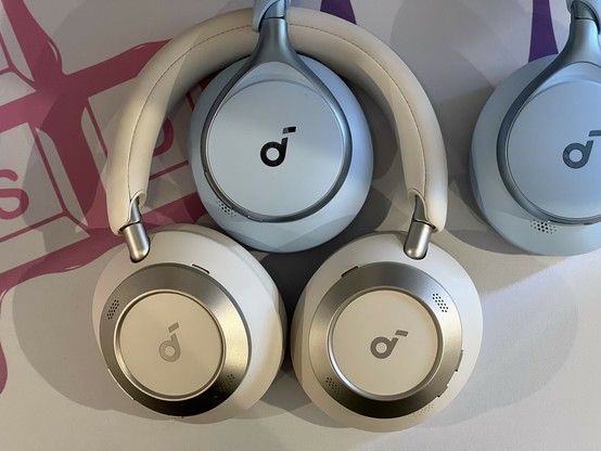 Two pairs of chunky over ear headphones, one curvy and blue nestled in a second pair of white and silver. Both from the same brand.