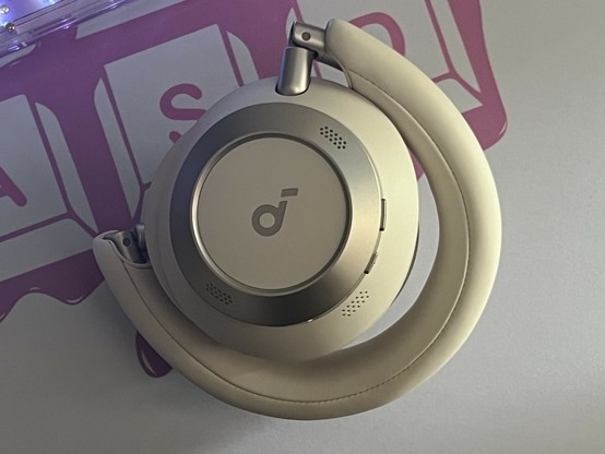 A pair of white and silver over ear headphones folded into a neat little bundle with the cups stacked upright and facing each other.