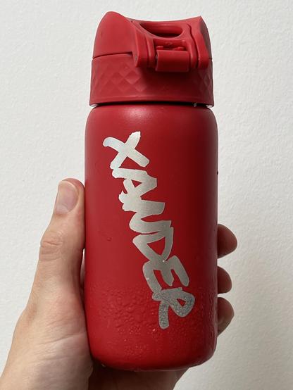 A vibrant water bottle with a silver vinyl name decal stuck onto it. The silver looks like the metal of the bottle, and feels very slick!