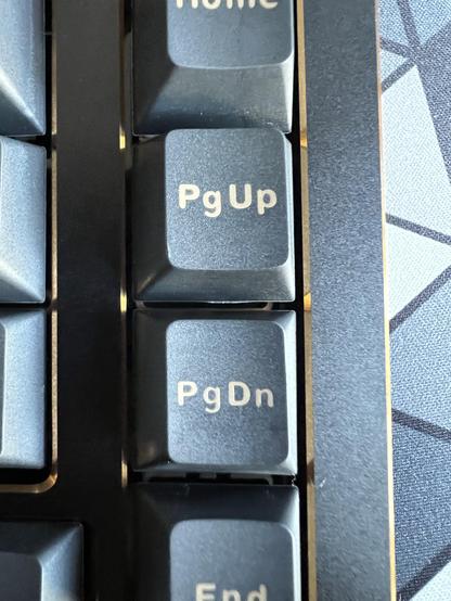 An extreme closeup of the PgUp and PgDn keys of a keyboard, the font sizes look different, the letter spacing is weird, the vertical alignment seems different between the keys and the overall impression is quite unpleasant.