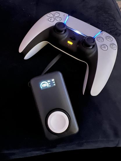 A small portable battery attached to a PS5 controller via a very short USB cable.