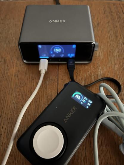 A small portable USB battery connected to a desktop charger. The battery is pulling 15W and its little LCD displays suggests a downstream device is pulling 7W.