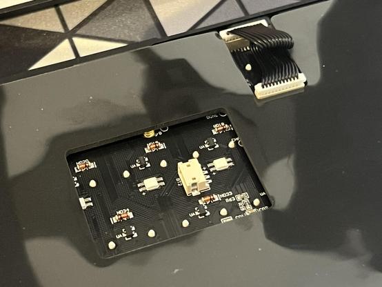 The JST battery and USB daughter board connectors peeking through the padding layer on the underside of a keyboard PCB. 