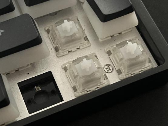 The arrow keys in the KB65HE, the left switch has been removed revealing a large hole for a central peg, a top/side LED placement and two smaller holes for the locating legs.