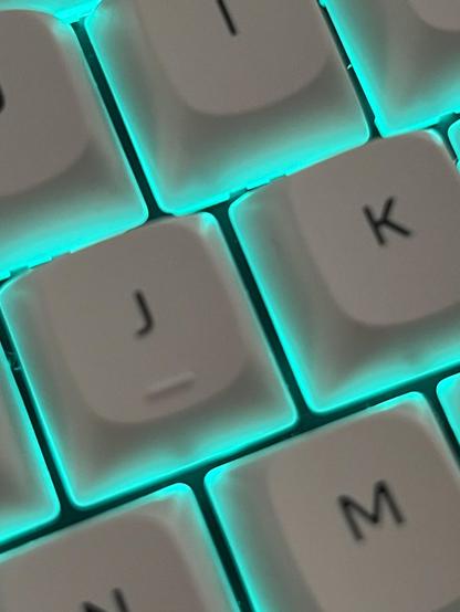 White J and K keys on a mechanical keyboard, beautifully lit by a teal glow from beneath.