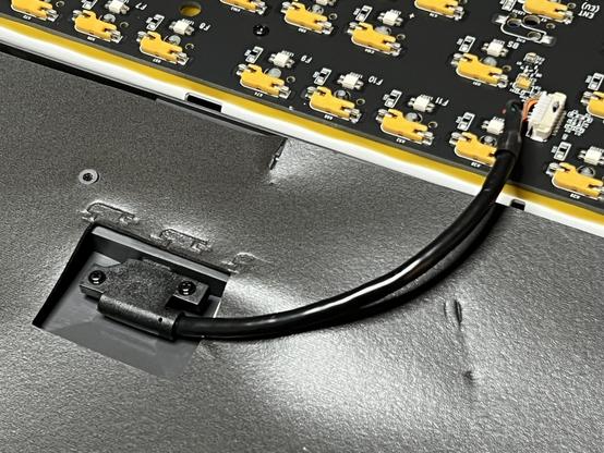 A closeup of the insides of the Ducky One 3 Pro, showing a short pigtail USB C port screwed to the bottom and connected to a JST connector on the board.