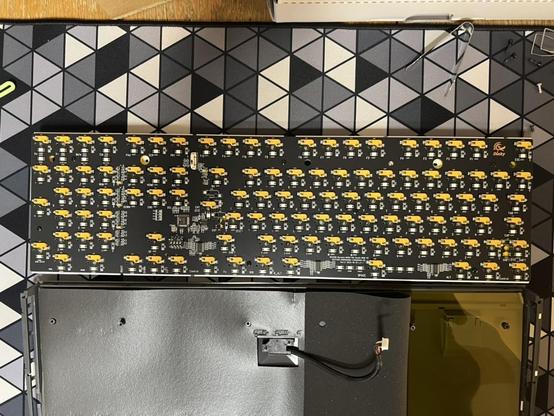 A full shot of the Ducky One 3 Pro keyboard PCB showing an array of yellow switch sockets among other components. The bottom half is laid below it with the USB connector disconnected.