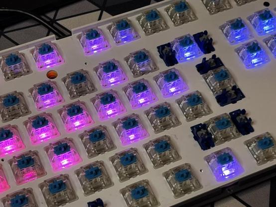 Closeup of the Ducky One 3 Pro with all of the keycaps removed. Some switches are lit up in blue/purple showing some minimal bright spots.